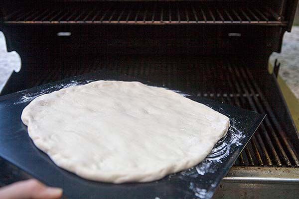 Placing the pizza dough on the grill