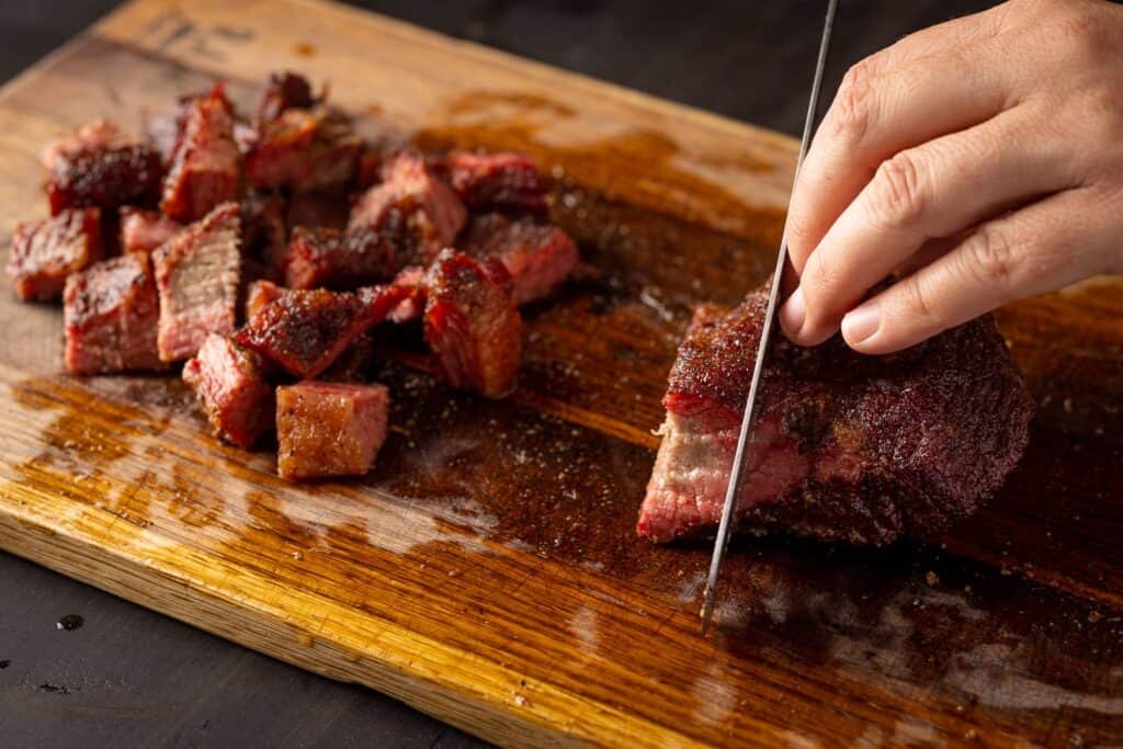 cutting the smoked brisket into 1-inch cubes. in making poor mans burnt ends 