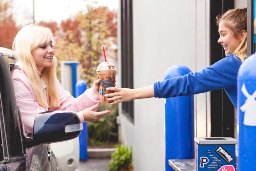 A woman taking Dutch bros coffee in the counter