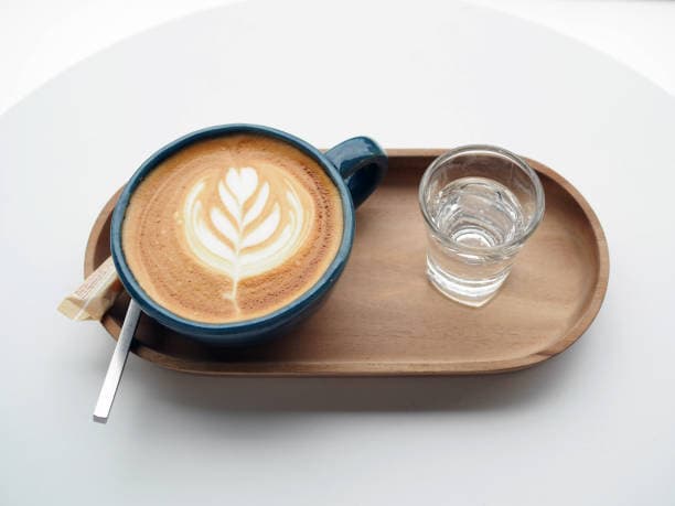 A glass of water with a cup of latte